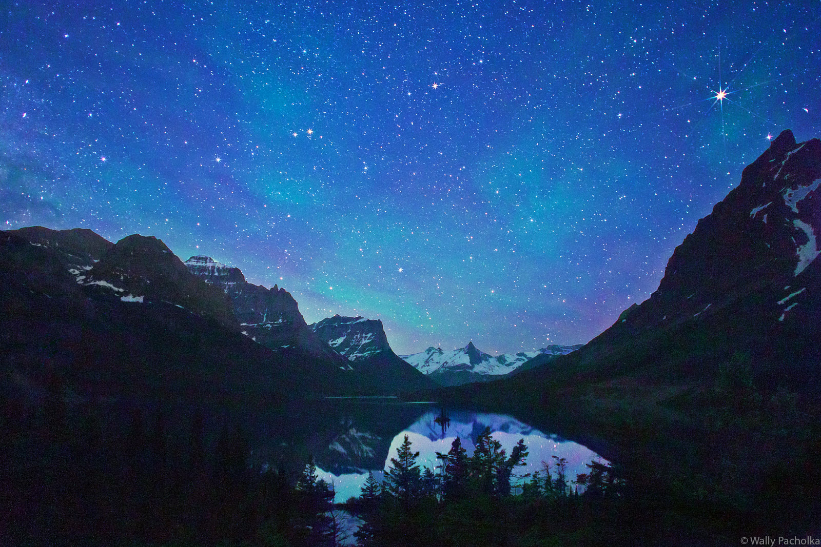 Green Air Glow caused by ion beams from the sun lights up the night above Goose Island in Glacier National Park.